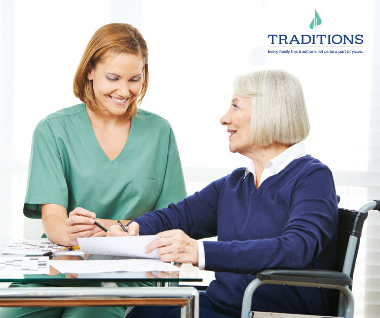 A caregiver and elderly woman sitting at a table working on puzzles