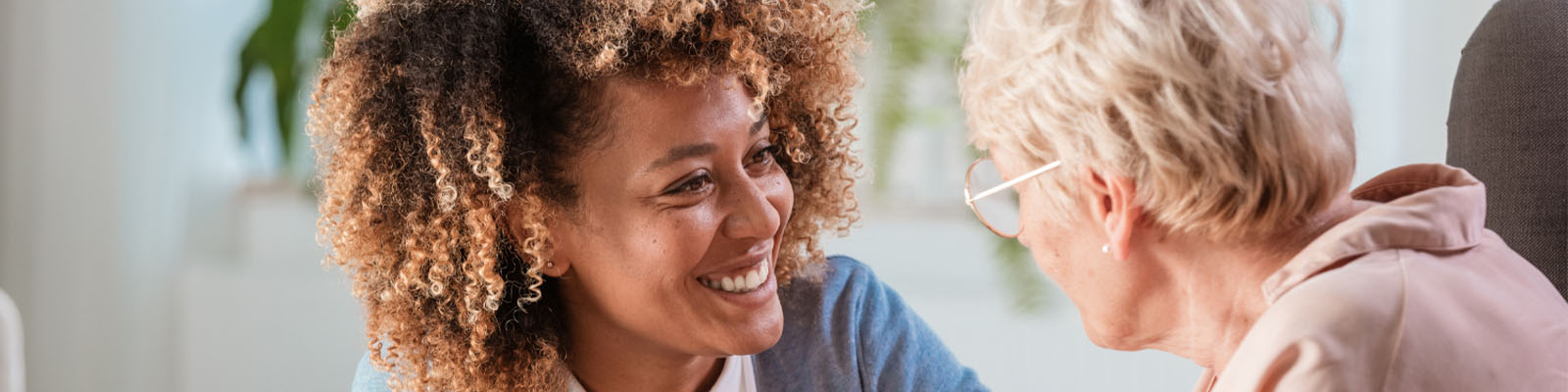 A female senior memory care patient sitting and looking at her female nursing assistant